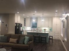 a living room filled with furniture next to a kitchen and breakfast nook area on top of a hard wood floor