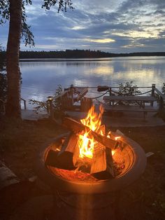 a fire pit sitting on top of a lush green field next to a body of water