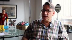 a man sitting in front of a glass table next to two figurines on the wall