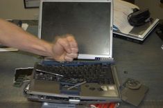 a person is removing the screen off of a laptop that's sitting on a desk