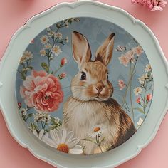 a plate with a rabbit painted on the side and flowers in the background next to it