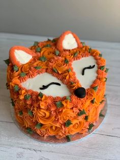 a cake decorated with orange flowers and a fox face