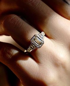 a woman's hand holding an engagement ring with two diamonds on the top and bottom