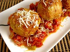 three meatballs covered in tomato sauce and parmesan cheese on a white plate