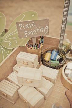 there are many small wooden boxes and pencils in the box on the table next to it is a sign that says pixie painting