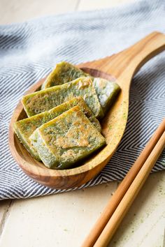 some food on a wooden plate with chopsticks next to it and a blue towel