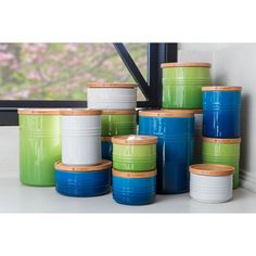 a group of green and blue canisters sitting next to each other in front of a window