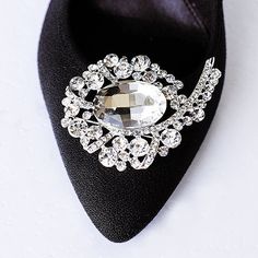 a black shoe with a crystal brooch on it