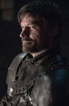 a man with a beard wearing armor in the dark