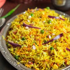 a plate full of rice and vegetables on top of a table with other dishes in the background