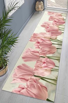 pink tulips are on the floor next to a potted plant