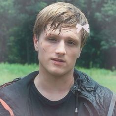 a young man wearing a black jacket and pink bow in his hair is looking at the camera