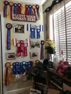 there are many ribbons hanging on the wall in this room with pictures and flowers behind them