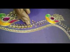 a person is working on an elaborate headpiece with beads and stones in gold, red, green and yellow colors