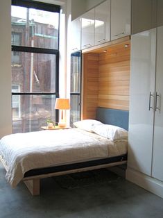 a bedroom with a bed, dresser and large window in it's side wall