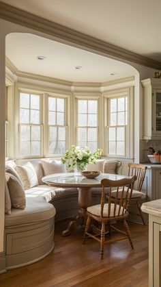 a living room filled with furniture and a round table in front of two large windows