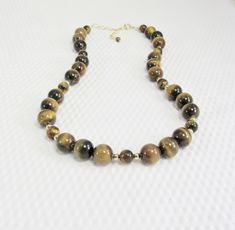 "This necklace showcases the contrasting bands of color and lustre in the large golden brown tiger eye beads in two sizes and separated with polished 14K gold filled accent beads. It is finished with a gold filled spring ring and attached 2.5\" gold filled adjustable chain. The necklace can be worn between 17.5 inches and 20 inches in length (44 to 51 cm). This is a timeless necklace that is easily worn with black, cream, white, brown, and gold blouses or sweaters--a very versatile piece! It shi Brown Round Gemstone Beads Jewelry, Brown Gemstone Jewelry With Round Beads, Brown Natural Stones Round Jewelry, Brown Gemstone Beaded Necklace, Brown Jewelry With Polished Round Beads, Brown Polished Beads Jewelry Gift, Brown Single Strand Round Jewelry, Brown Round Single Strand Jewelry, Brown Gemstone Necklaces With Round Beads