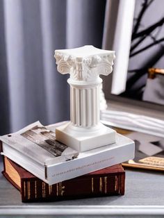 a white statue sitting on top of a stack of books