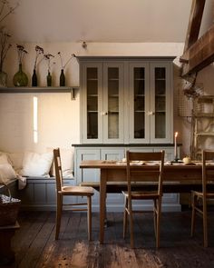 a table and chairs in a room with wooden flooring, built - in cupboards and shelves