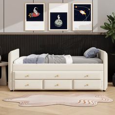 a white day bed sitting in a bedroom next to two pictures hanging on the wall