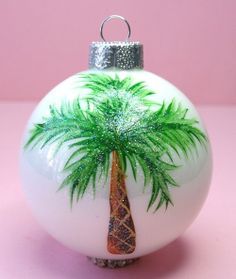 a glass ornament with a palm tree painted on it