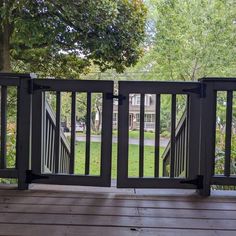 a wooden deck with black railings and trees in the background