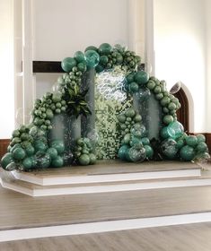 an arch made out of green balloons and greenery