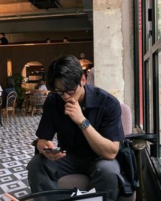 a man sitting on a chair looking at his cell phone