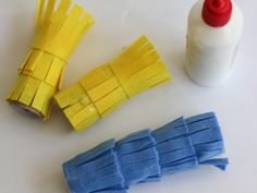 some yellow and blue pieces of paper next to a bottle of toothpaste on a white surface