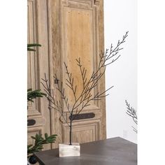 a vase with some branches in it sitting on a table next to a wooden cabinet