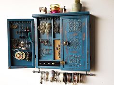 a blue cabinet with jewelry hanging from it's sides