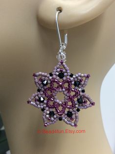 a pair of beaded earrings on top of a mannequin head with beads in the shape of a star