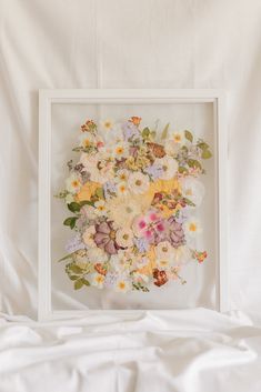 an arrangement of flowers in a white frame