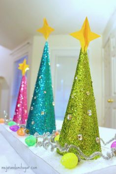 three brightly colored christmas trees sitting on top of a table