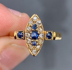 Petite 18ct gold Old Cut diamond & natural sapphire marquise/ navette Victorian Ring  The ring is set with rose cut diamonds and natural sapphires- NATURAL VIVID  Blue Sapphires Surrounded by Rose Cut Diamonds Circa  approx. 1870-80 18K  GOLD - Unmarked but tested Size 6.5 - easily sizable 3mm natural high domed cushion cut blue sapphire securely held with prongs in center 2- approx. 2mm sapphires top and bottom , 2- approx. 2.4mm one on each side   12 x approx. 2 mm diamonds = .24ct. approx. to Yellow Gold Sapphire Ring With Marquise Cut Rose Diamonds, Yellow Gold Sapphire Ring With Rose Cut Diamonds, Marquise Sapphire Diamond Ring With Rose Cut Diamonds, Marquise Sapphire Ring With Rose Cut Diamonds, Gift Sapphire Marquise Ring With Rose Cut Diamonds, Gift Marquise Cut Sapphire Ring With Rose Cut Diamonds, Marquise Cut Sapphire Ring With Rose Cut Diamonds, Gift Marquise Sapphire Ring, Marquise Sapphire Ring As Gift