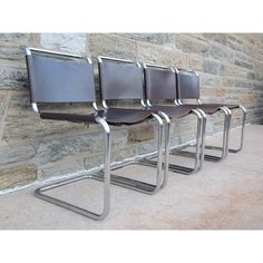 four chairs are lined up against a stone wall