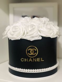 a chanel hat with white roses on top and pearls around the bottom, sitting on a table