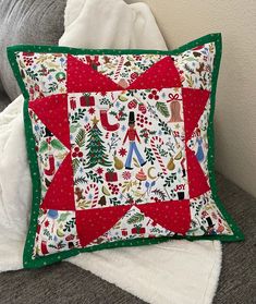 a christmas themed pillow sitting on top of a couch next to a white throw pillow