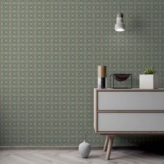 a white dresser sitting next to a wall with a green and blue pattern on it