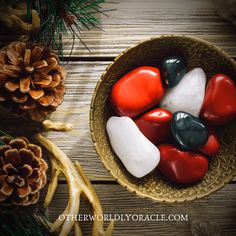 red, white and blue rocks in a bowl next to pine cones on a wooden table