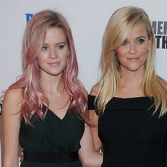 two women standing next to each other on a red carpet