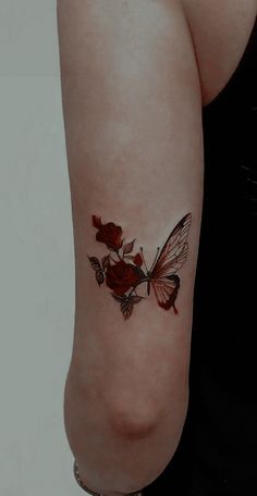 a woman with a butterfly tattoo on her left arm and red roses in the middle