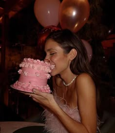 a woman is biting into a pink cake