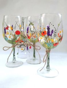 three wine glasses with flowers painted on them