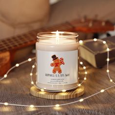 a lit candle sitting on top of a wooden table next to a string of lights