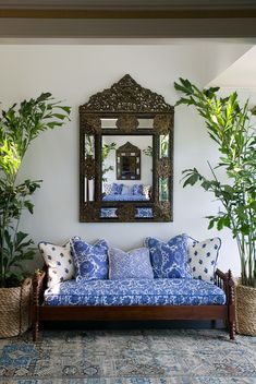 a living room filled with furniture and lots of greenery next to a large mirror