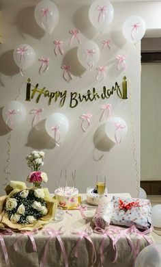 a table topped with lots of balloons and flowers next to a sign that says happy birthday