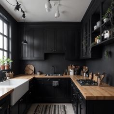 a kitchen with black cabinets and white counter tops, wooden counters and an area rug on the floor