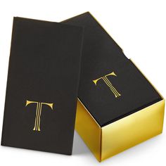 a black and gold box with the letter t on it's side, open