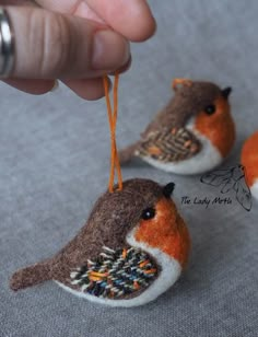 two small birds are hanging from strings on a string that is being held by someone's hand